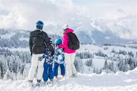 Familia esquiando en una estación de esquí en los Pirineos con montañas nevadas al fondo.