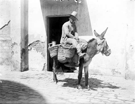Dibujo o foto antigua de un vendedor ambulante de leche con cántaras o un cabrero ordeñando sus animales en las calles de Granada (años 1920-30).