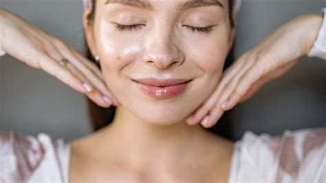 Mujer sonriente con cabello brillante y piel sana, comiendo un puñado de frutos secos