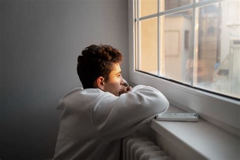 Fotografía de un adolescente pensativo mirando por la ventana.
