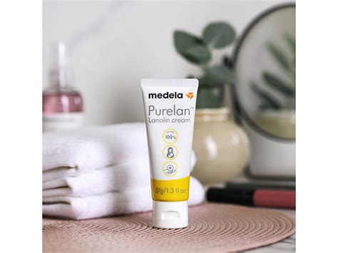 Tubo de crema Medela PureLan 100 sobre un fondo suave, con hojas verdes o elementos naturales que sugieran naturalidad y cuidado.