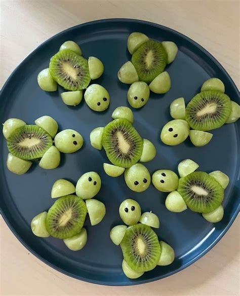 Mellizos sentados en tronas, cada uno con trozos de frutas y verduras sobre la bandeja, comiendo con las manos (BLW)