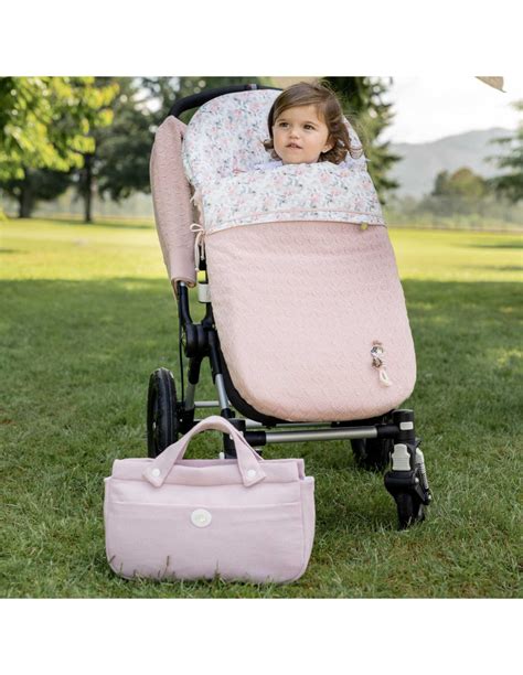 Foto de un saco universal para silla de paseo en un carrito, mostrando las aperturas para arneses