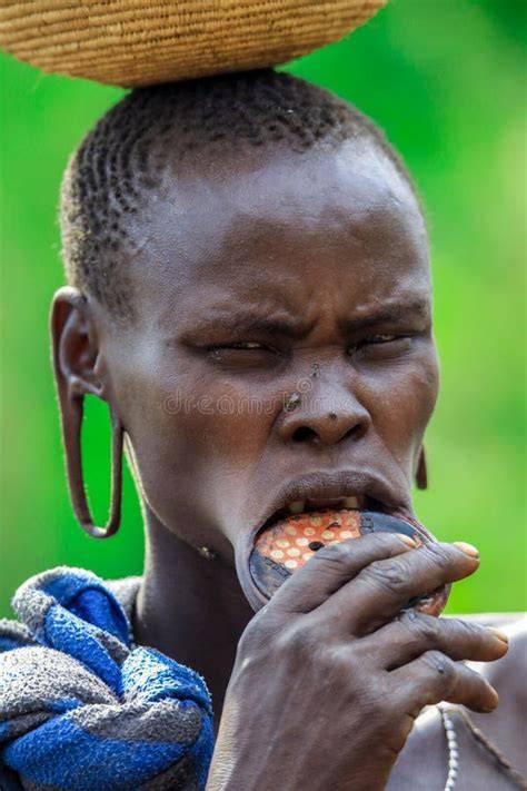 Mujer africana en un entorno rural, posiblemente cultivando o en una situación que refleje las presiones sociales.