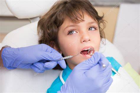 Odontólogo pediátrico examinando los dientes de un niño