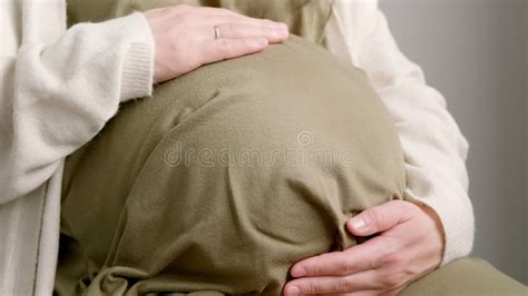 Una mujer embarazada tocando su barriga, con una expresión de ternura y sorpresa, representando la sensación del hipo fetal.