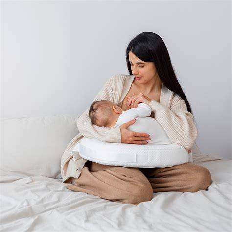 Madre amamantando a su bebé usando un cojín de lactancia