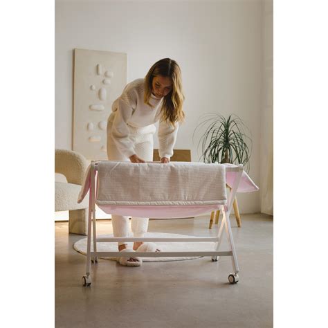 Minicuna de tijera con bebé durmiendo cómodamente en el interior, con diseño textil