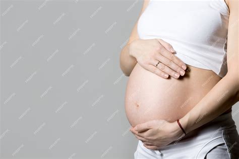 Fotografía temática de una mujer embarazada tocándose el abdomen con expresión de dolor