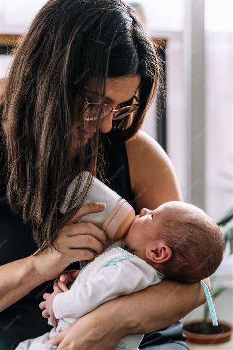 Fotografía: Madre alimentando a su bebé con un biberón en una posición semi-vertical.
