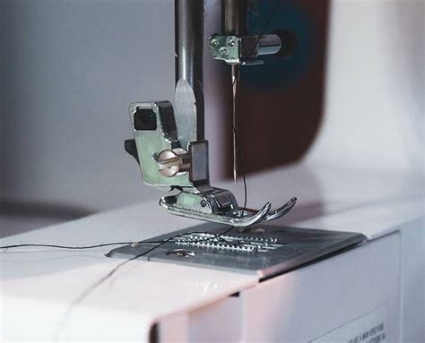 Detalle en primer plano de una máquina de coser realizando el acabado de un ojal reforzado