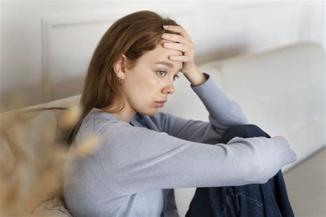 Mujer embarazada en el tercer trimestre con expresión de preocupación o ansiedad, sentada o acostada incómoda