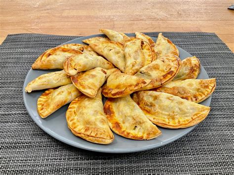 Plato de empanadillas doradas y crujientes recién salidas del horno listas para servir.