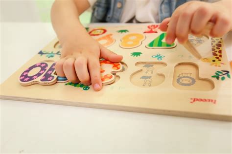 Niños haciendo un puzle de números y figuras, y bolos caseros numerados.