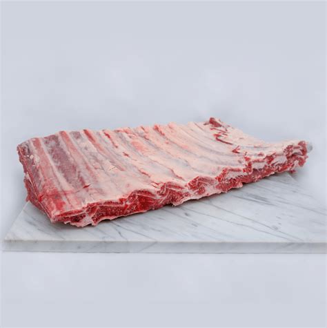 Foto de un costillar de cabrito crudo en una fuente de horno, listo para ser aderezado.