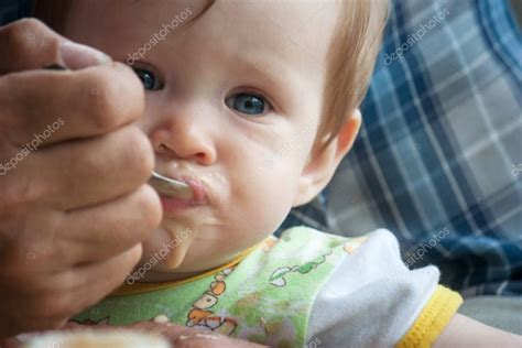 Bebé sonriendo mientras come puré de frutas con una cuchara