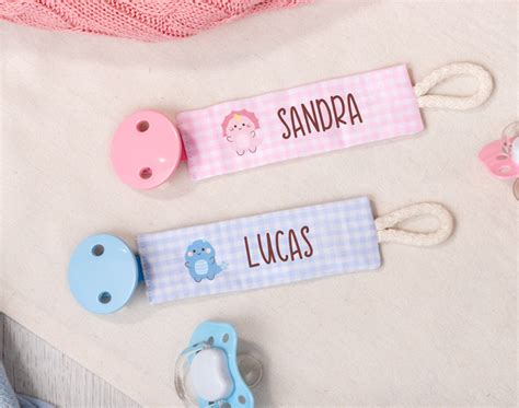 Ilustración de un bebé sonriente con una cinta sujeta chupetes colorida.