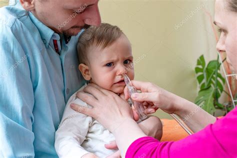 Padre usando aspirador nasal en bebé