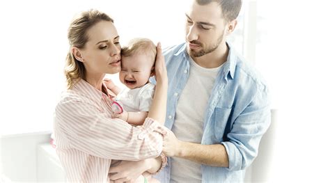 Bebé siendo consolado por sus padres, con énfasis en el abdomen