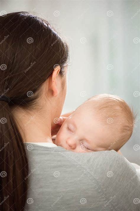 Madre lactante con bebé, con un enfoque en la expresión facial de la madre que podría indicar preocupación estética