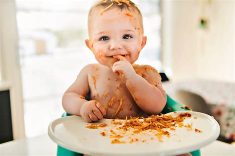 Bebé de 9 meses comiendo trozos de fruta con las manos