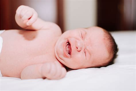 Bebé llorando con cólicos, sostenido por sus padres