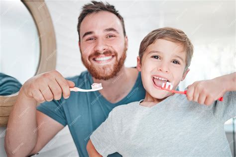 Imagen de un padre o madre ayudando a su hijo pequeño a cepillarse los dientes de leche.
