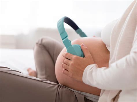 Bebé escuchando música en el vientre materno, con auriculares o una madre cantando