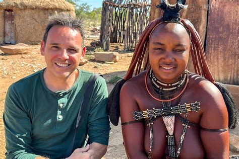 Mujer de la tribu Himba con su hijo, rodeada de la comunidad.