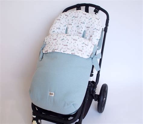 Esquema de un saco de silla de paseo mostrando los puntos de sujeción y arneses.