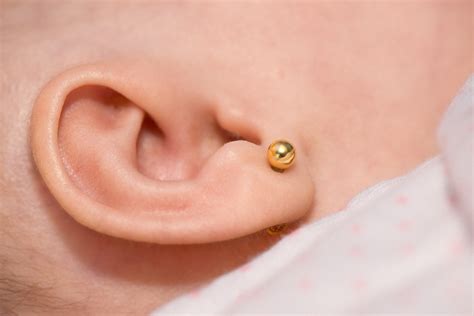Primeros planos de orejas de bebé con pendientes recién puestos, mostrando la higiene