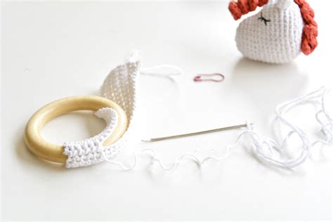 Esquema de las partes principales de un sonajero: cabeza amigurumi, aro de madera forrado y cascabel interno.