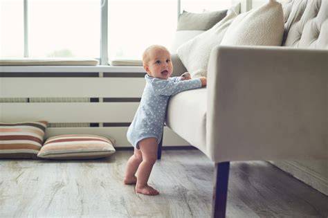 Bebé de 8 meses intentando levantarse apoyado en un sofá
