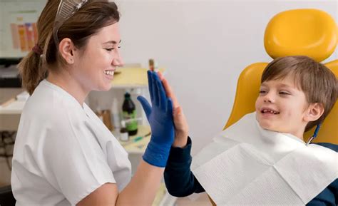Niño sonriendo mientras un dentista infantil le revisa los dientes de forma lúdica