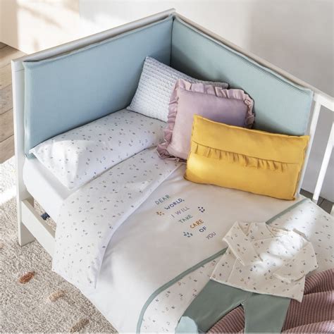 Conjunto de textiles para minicuna: sábanas, protector y colcha.