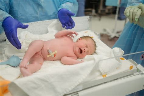 Bebé recién nacido siendo pesado por un profesional médico