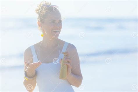 Mujer embarazada feliz en la playa usando un traje de baño