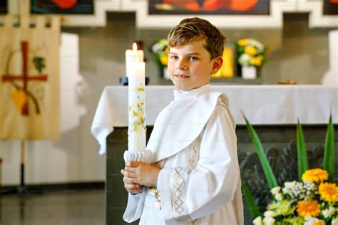 Niño en su Primera Comunión mostrando una cruz
