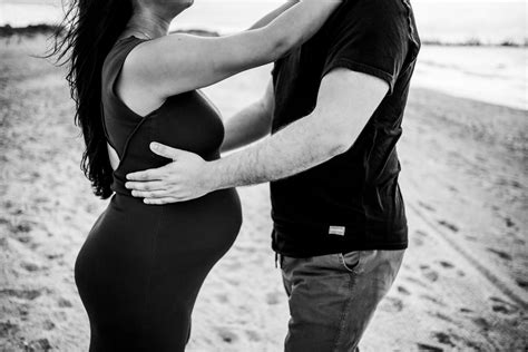 Fotografía natural de una pareja embarazada en una playa tranquila con dunas
