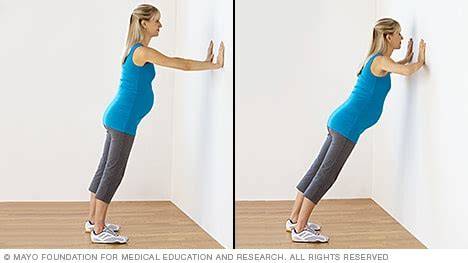 Mujer embarazada haciendo flexiones en la pared