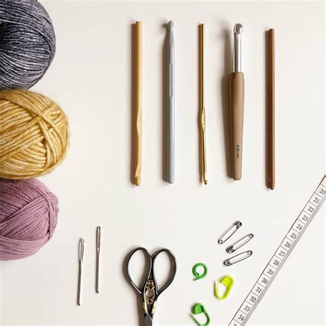 Esquema de materiales básicos para tejer a crochet: ganchillos, ovillos de algodón y cinta métrica