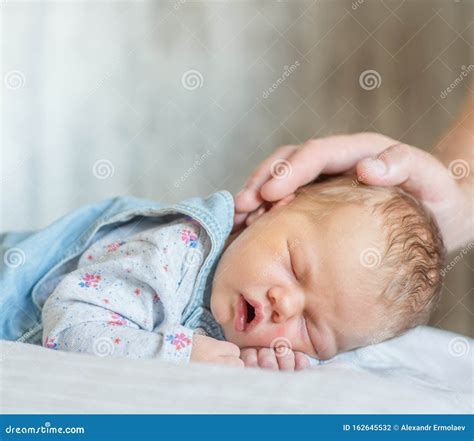 Padre acariciando la mano de su bebé para ayudarle a relajar los puños