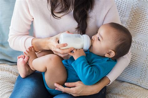 Madre dando un biberón a su bebé mientras juega con él