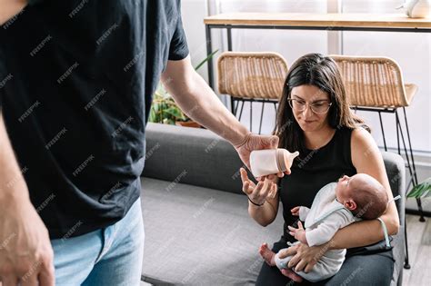 Padre ofreciendo un biberón a su bebé mientras la madre está ausente.