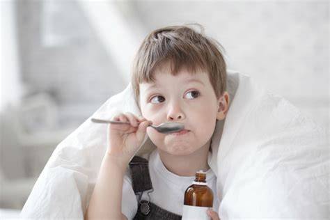 Niño tomando jarabe natural para la tos con una cuchara