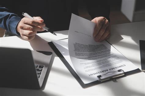 Persona rellenando formularios en una oficina, con documentos y ordenador