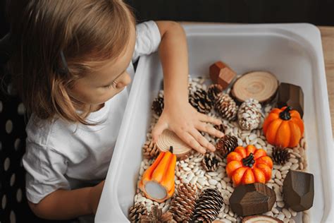 Bebé explorando una cesta sensorial con elementos de otoño