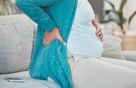 Mujer embarazada relajándose en un sofá con una compresa térmica