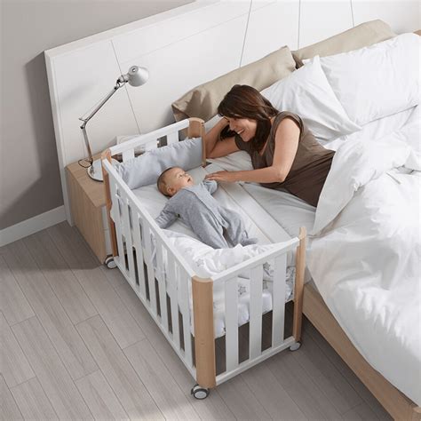 Esquema de cuna de colecho anclada a la cama de los padres con un bebé durmiendo