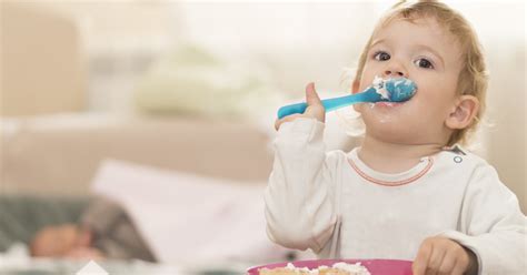 bebé de 18 meses comiendo de forma autónoma en la mesa familiar